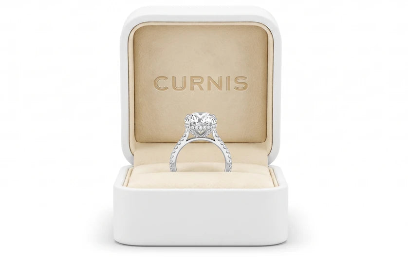 Il cofanetto Curnis bianco aperto, con il logo impresso nel camoscio crema e un anello solitario con diamante